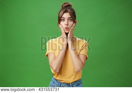 Silly Cute And Tender Young Female Model With Cleacn Skin Folding Lips, Pressing Hands To Cheeks And
