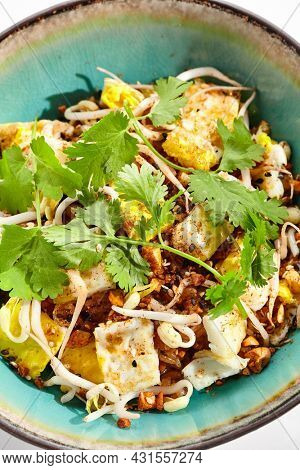 Traditional Chinese dish - fried rice with egg and vegetable. Asian wok with rice and shredded omelette on white background. Nasi goreng with egg on isolated background with shadows