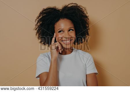 Keep It In Mind. Portrait Of Young Positive Pensive African Woman With Curly Hair Touching Temple Wi