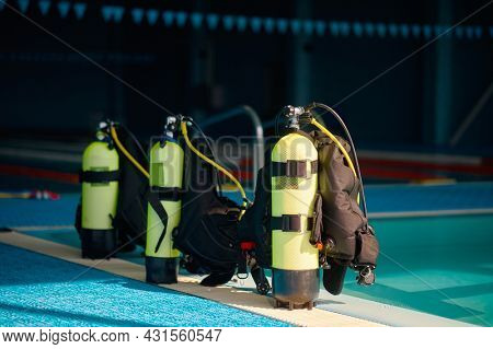 Three oxygen tanks at poolside, diving equipment