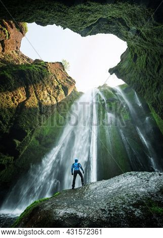 Man in the cave near the Gljufrabui (Gljufrafoss) waterfall, Iceland, Europe. Famous tourist attraction near Seljalandsfoss waterfall. Landscape photography