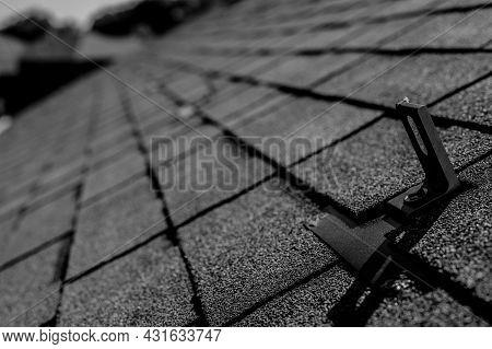Residential Asphalt Shingle Roof With Metal Anchors Installed For The Installation Of A Solar Panel 