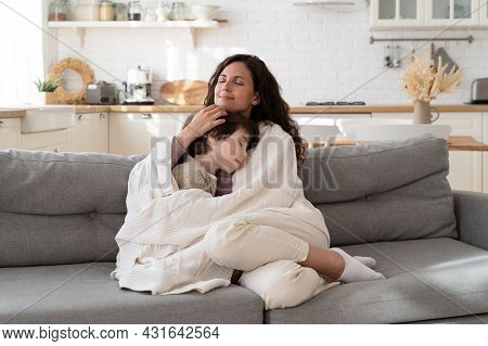 Young Mom Sit On Cozy Couch Relax With Preschool Child Covered With Blanket Bonding With Kid On Week