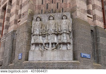 Amsterdam, Netherlands - August 13, 2021: Gray Statue-fresco Of 3 Sailors Holding Anchor At Basse Of