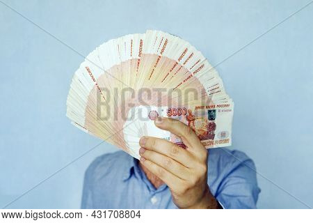 Russian Banknotes Rubles In Hand. 5000 Banknotes Folded Fan Cover The Face Of The Businessman.