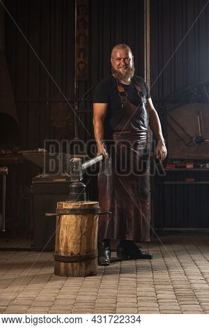 Full Ength Portrait Of Bearded Man, Blacksmith Working On Creating Handmade Metal Product At Family 
