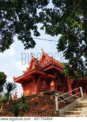 Temple Of Red Color In Thailand. The Facade Of The Temple Is Decorated With Figures Of Dragons And G