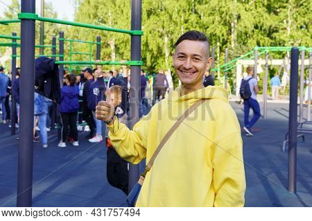 A Young Cheerful Man In A Yellow Jacket At A Sports Event. Selective Focus