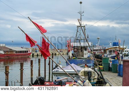 Red Flags And Fishing Boats At The Dock In The Port Of Sassnitz On The Island Of Rugen In The Baltic