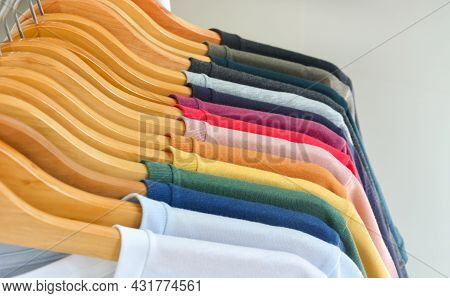 Close Up Collection Of Color T-shirts Hanging On Wooden Clothes Hanger In Closet Or Clothing Rack Ov
