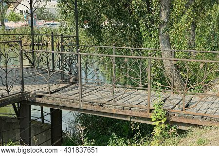 Gray Wooden Bridge With Metal Forged Handrails Over The Reservoir To The Gazebo On The Street Among 