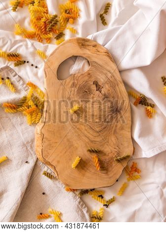Cutting Board Curved Shape Of Olive Tree, Scattered Around Pasta, Garlic, Pepper. They Lie On A Crud