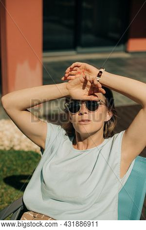 Portrait Of Mid Adult Woman Wearing Sunglasses. Confident Lady Sitting On Chair And Looking At Camer