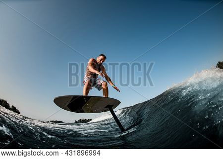 Adult Man Ride Down The Wave With Hydrofoil Foilboard On Background Of Blue Sky