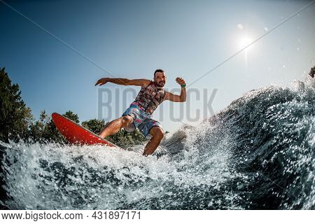 Man Having Fun And Ride Down On Splashing River Wave On Foilboard At Summer Day