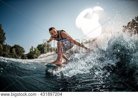 Close-up Of Man Riding Down On Splashing River Wave On Foilboard And Having Fun