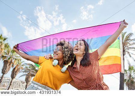 Young Lesbian Couple Celebrates Pride Day With Rainbow Flag. Concept Of Homosexuality, Gay.