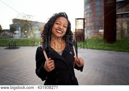 Latina Businesswoman Smiles Happily Looking At The Camera. The Young Woman Is Standing Next To A Mod