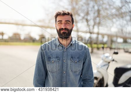 Portrait Of A Young Spanish Man Looking At The Camera. The Man With Cheerful Smile Is In Front Of Hi