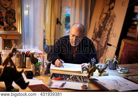 Artist Working In The Studio. Older Man Painting A Picture Using A Magnifying Glass In A Creative An