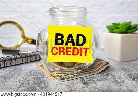Some Banknotes In A Glass Jar, With Its Lid Near It, With The Words, Bad Credit On It. Concept Of Un
