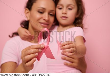 Close-up Of A Pink Satin Ribbons On Blurred Woman And Girl Hugging Each Other. World Breast Cancer A