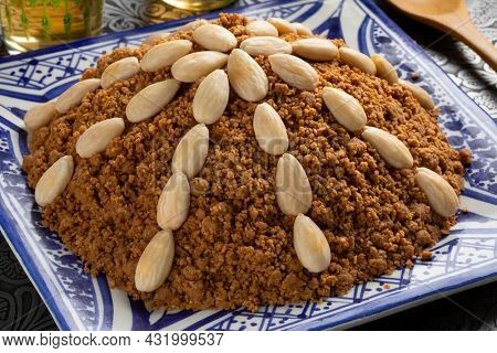 Dish with traditional Moroccan homemade sellou decorated with roasted almonds close up