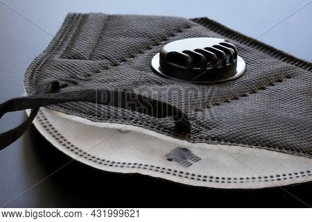 A Black Respirator With Filter And Valve Lies On A Gray Uniform Background. Respirator Protection Cl