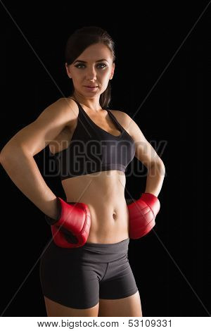Beautiful sporty woman posing wearing boxing gloves looking at camera on black screen