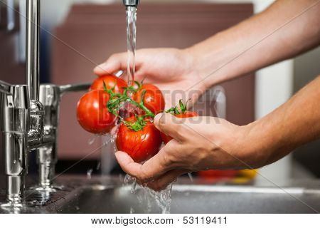 Kitchen porter washing tomatoes in professional kitchen