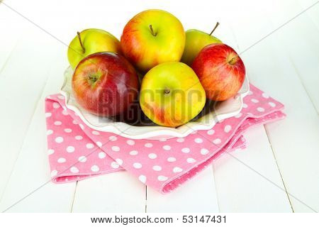 Juicy apples on plate on white wooden table