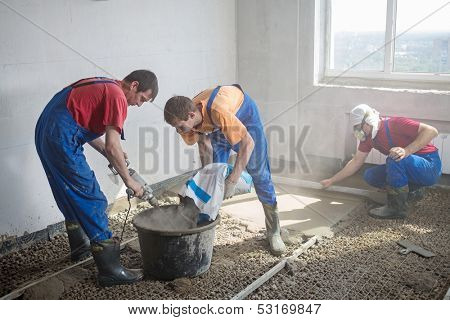 Three worker prepare the mixture and pouring the floor