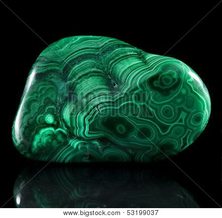 Polished malachite stone close up with reflection on black surface background