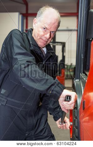 Man changing a tyre of a forklift, putting force on a torque wrench, tightening the wheel nuts.