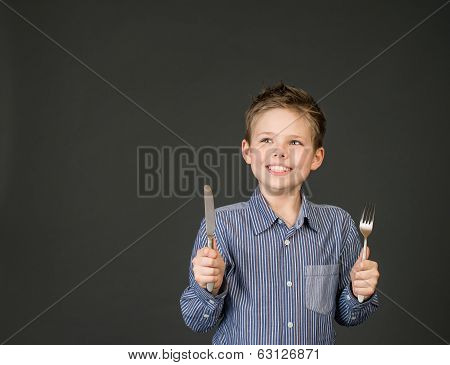 Little boy with fork and knife. Hungry child.