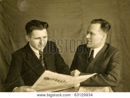 LODZ, POLAND, CIRCA 1940's: Vintage photo of two men, one of them reading a soviet newspaper 
