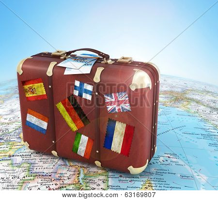 Old Suitcase With Air Ticket And Striples Flags On Blurred World Map And Sky In Background
