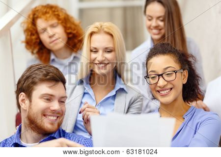 business, office and startup concept - smiling creative team with papers and take away coffee on staircase