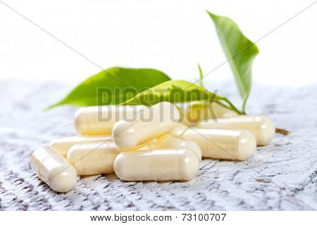 Capsules on white wooden background.