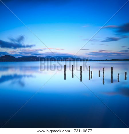 Wooden Pier Or Jetty Remains On A Blue Lake Sunset And Sky Reflection On Water. Versilia Tuscany, It
