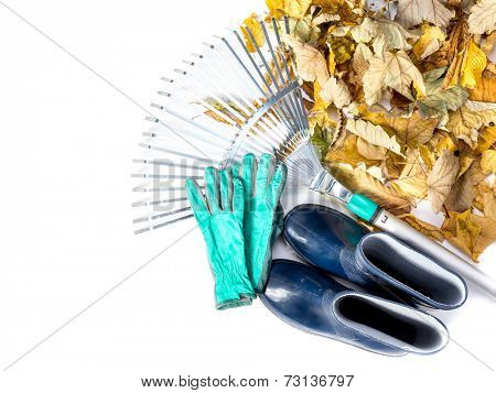 Pile of dead fall leaves, fan rake, pair of gumboots, and pair of gardening gloves all shot on white