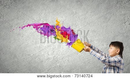 Young boy splashing colorful paint from bucket