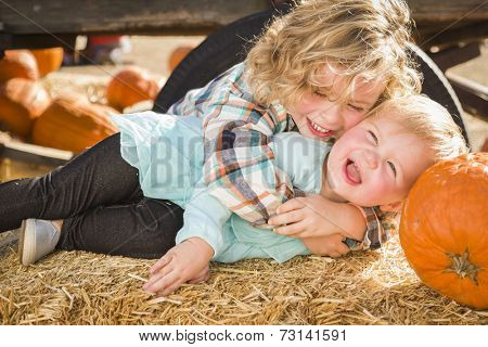 Sweet Little Boy Plays with His Baby Sister in a Rustic Ranch Setting at the Pumpkin Patch.