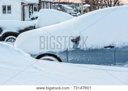 A truck and a car in a driveway in a suburban neighborhood buried in new fallen snow.