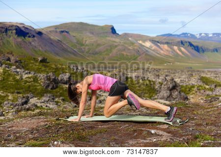 Exercising fitness woman doing exercises in nature. Girl doing mountain climbers exercise training outside in amazing landscape on Iceland. Fit female Asian Caucasian athlete sport model .