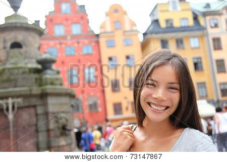Woman portrait in Europe, Stortorget, Stockholm, Sweden. Happy candid travel tourist girl on big square in Gamla Stan, the old town of Stockholm, Sweden.