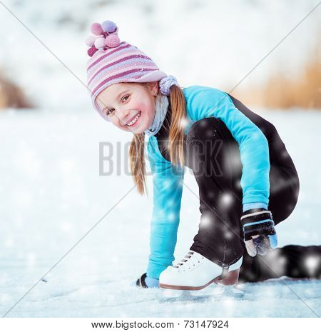 happy  cute little girl in thermal suits sits on the ice in winter outdoors
