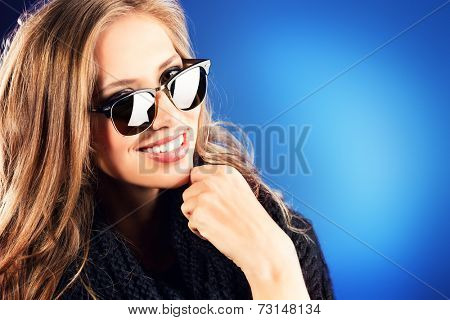 Close-up portrait of a smiling young lady with beautiful hair wearing black sunglasss.