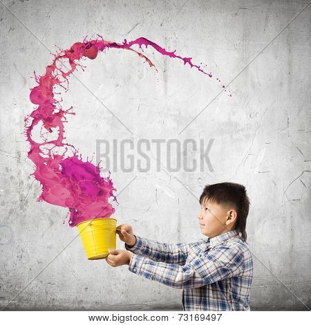 Young boy splashing colorful paint from bucket