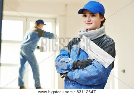 female plasterer painter portrait at indoor wall renovation decoration stopping with spatula and plaster